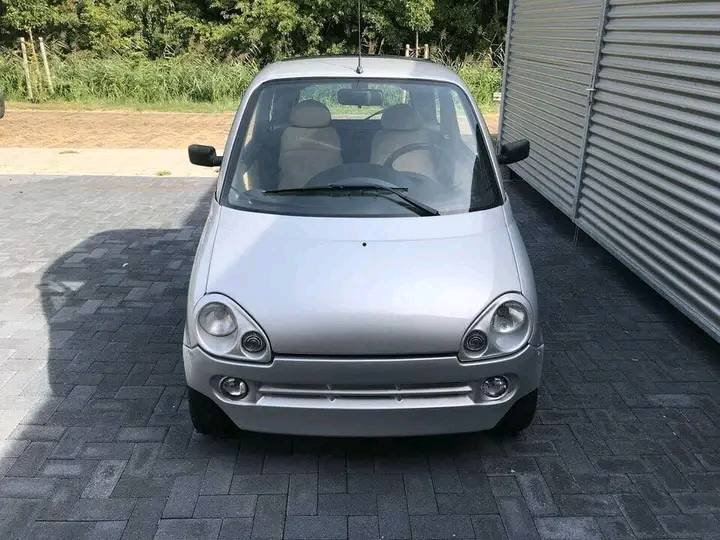 Vue avant droite de la Microcar grise avec éclairage et calandre visibles