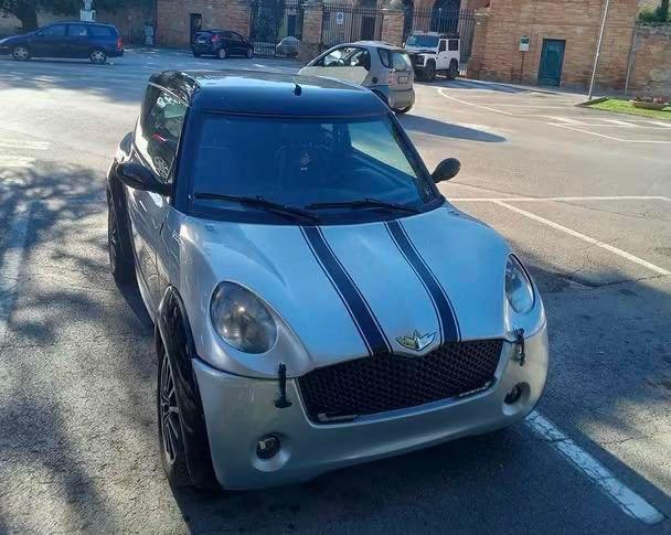 Vue avant droite du microcar gris sur parking urbain
