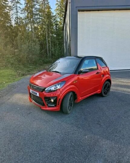 Vue avant droite de la microcar rouge garée, pare-chocs et phares visibles