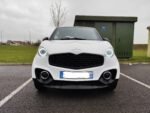 Vue avant droite de la microvoiture blanc toit noir stationnée