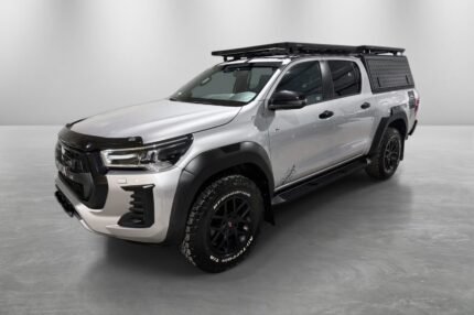 Profil latéral d'un pick-up gris sur terrain, châssis surélevé et roues tout-terrain