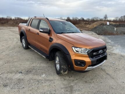Ford Ranger Wildtrak orange vu de profil avant, benne et barres de toit